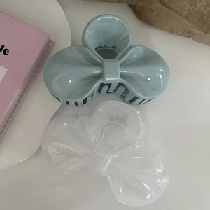 Detail of macaron blue and transparent bow hair claws on a clean aesthetic background