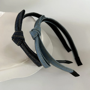 Close-up of denim knotted headbands with yellow stitching on a ceramic display
