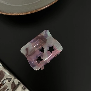 Detail of purple marble acetate hair claw clip featuring three hollow star patterns