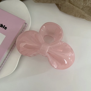 Close-up of pink translucent jelly bow hair claw clip on a stylish lifestyle background