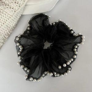 Detail of black organza scrunchie with delicate white pearl edges on a stylish background