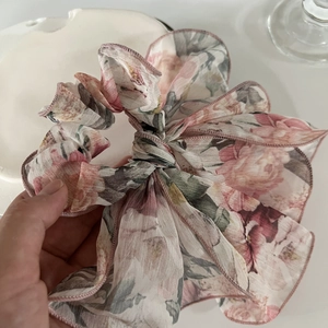 Détail macro du chouchou en mousseline florale avec imprimé rose et ruban