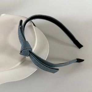 Detail of blue denim headband featuring single-sided bow knot and golden stitch details