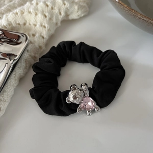 Detailed macro view of black fabric scrunchie with silver bear and pink heart gem