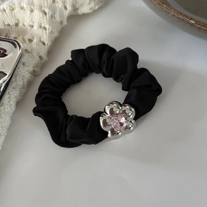 Detail of black scrunchie with silver flower metal charm and pink heart crystal