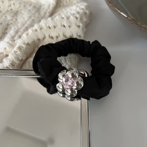 Detail of black elastic hair tie with silver flower charm and pink heart crystal centerpiece