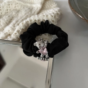 Close-up of black scrunchie with silver bear pendant holding a pink crystal heart