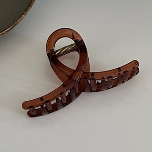 Detailed side view of amber resin hair claw clip with strong metal spring and large teeth