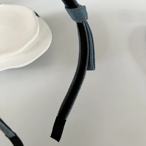 Detailed macro view of denim headband with golden stitching and blue bow accent