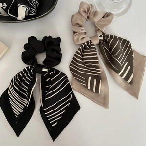 Détail de chouchous soyeux avec nœuds et rubans rayés élégants en noir et beige clair
