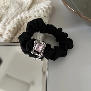 Detail of black silk scrunchie featuring a pink rectangular crystal and silver bear metal base