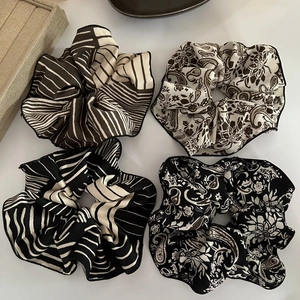 Detail showing high-quality satin scrunchies with black stripes and paisley patterns