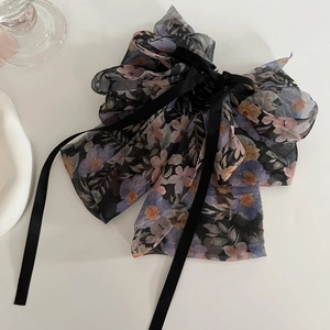 Detail der floralen Chiffon-Schleife mit langen schwarzen Bändern und romantischem Print