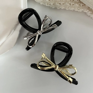 Dettaglio delle pinze per capelli nere con fiocchi metallici in oro e argento lucido