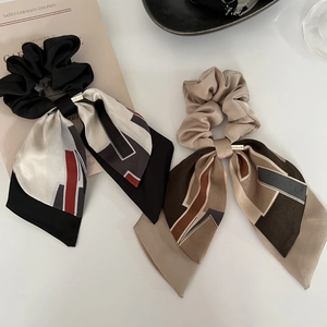 Détail de deux chouchous en satin de style français avec de longs rubans et breloques