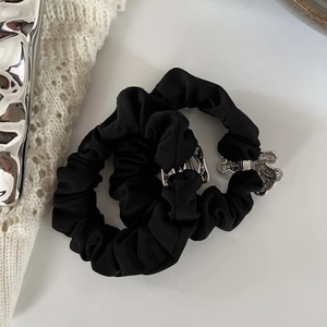 Elegant black scrunchie set with silver metallic bear pendant on white knit background