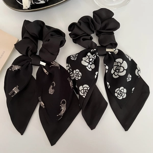 Détail de chouchous faits main avec motifs léopard et camélia sur satin noir élégant