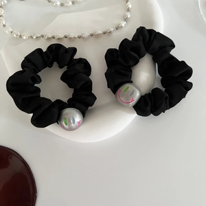 Détail de deux chouchous en satin noir avec perles grises ornées de motifs de smileys colorés