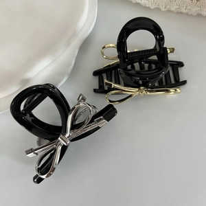 Eleganti mollette nere per capelli con fiocchi metallici oro e argento su vassoio