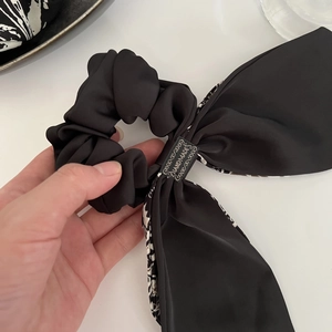 Gros plan sur un chouchou en satin noir avec étiquette faite main et texture soyeuse