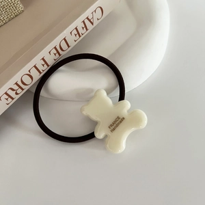 Detailed shot of cream-colored bear hair tie with France Handmade text on tray