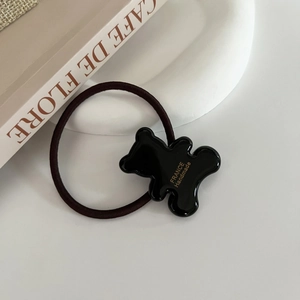 Detail of high-elasticity hair tie featuring a cute black acrylic bear with gold lettering