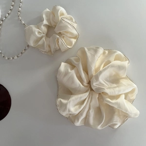 Elegant cream satin scrunchies set with sparkling rhinestones on minimalist grey background
