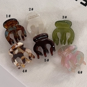 Detail shot of six colorful mini acetate hair claws with premium handmade engravings