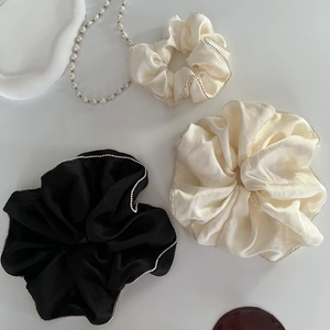 Detail of satin scrunchies with elegant bead trim in black and cream white colors