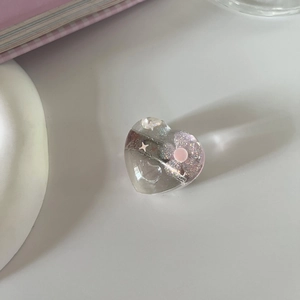 Makroaufnahme einer transparenten herzförmigen Haarspange mit rosa Glitzer und Sternen