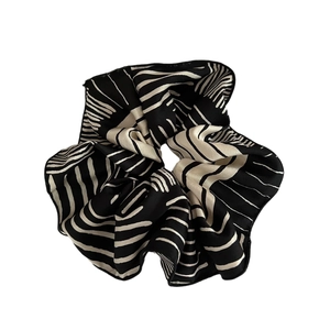 Classic black and white striped satin scrunchie with elegant pleated fabric texture