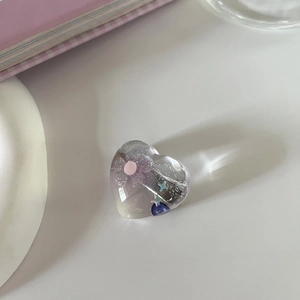 Detailaufnahme eines herzförmigen Harzrings mit lila Glitzer und Sternenmuster