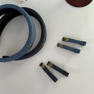 Detail of blue denim headbands and hair clips with vintage golden metal brand tags