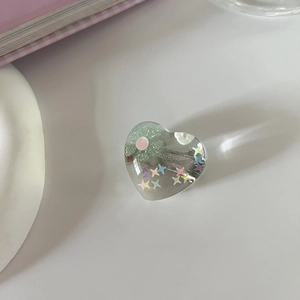 Detail einer transparenten Herz-Haarklammer mit rosa Sternen und silbernem Glitzer