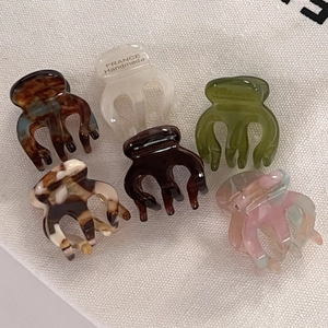 Close-up of six mini acetate hair claws with retro marble patterns and gold logo detail
