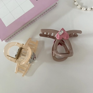 Detail of sweet heart-shaped hair claws with rhinestones in pink and cream beige