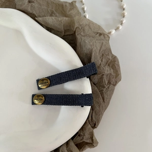 Close-up of vintage denim hair clips with gold metal buttons on elegant ceramic plate