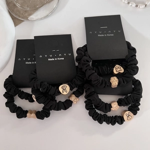 Minimalist black scrunchies with golden bear and rabbit charms on a display card