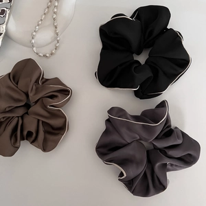 Three elegant satin oversized hair scrunchies in black, brown, and grey with white piping