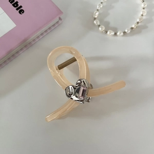 Detail of beige resin hair claw with silver heart and pink rectangular gemstone