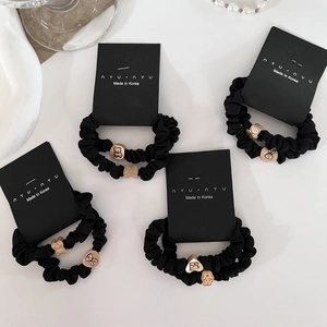 Detail of black elastic hair scrunchies with cute gold bear and rabbit charms