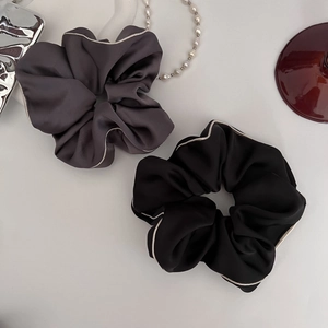 Detail view of premium satin scrunchies with contrast piping in black and dark grey tones