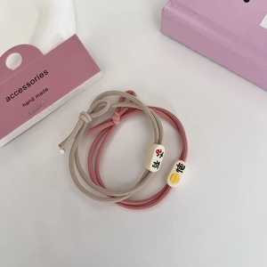 Détail d'élastiques à cheveux roses et kaki avec nœud et perles à motifs mignons