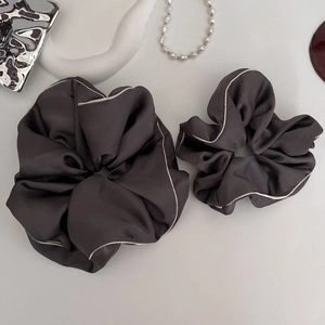 Close-up of charcoal grey satin scrunchies with elegant beige contrast edge detail