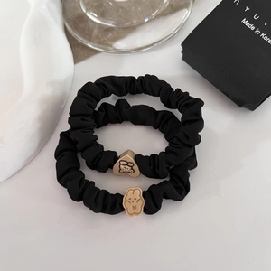 Detail of two black hair scrunchies with cute bear and rabbit metallic charms