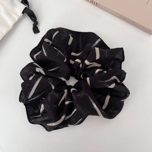 Macro detail of French chiffon oversized scrunchie with abstract lines on white fabric