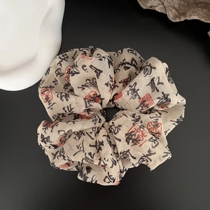 Close-up of beige scrunchie with Chinese calligraphy print and red seal design