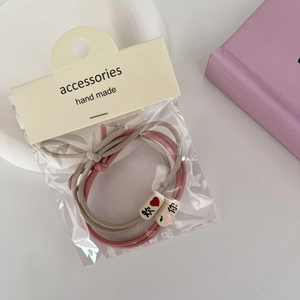 Détail d'élastiques à cheveux roses et beige avec perles motif pêche sur leur emballage