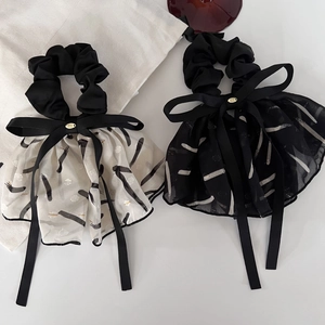 Close-up of elegant black and white bow scrunchies with ink print pleated ribbon details