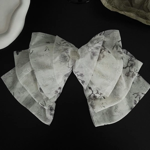 Detailed macro view of ink painting pattern on layered fabric bow hair clip accessory